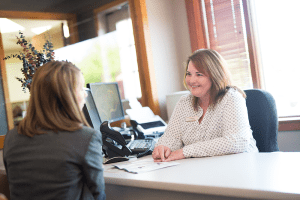 Woman sitting behind a counter consulting with a patient